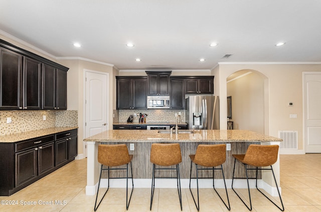 kitchen with light stone counters, sink, an island with sink, and appliances with stainless steel finishes