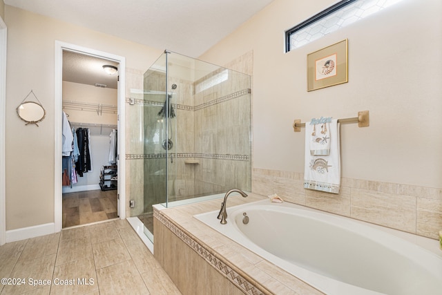 bathroom with a textured ceiling and independent shower and bath