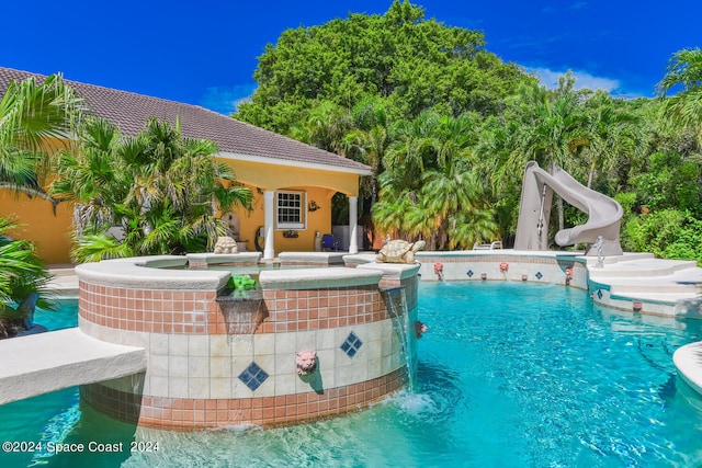 view of pool featuring an in ground hot tub and a water slide