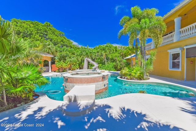 view of swimming pool featuring a water slide, a patio, and an in ground hot tub