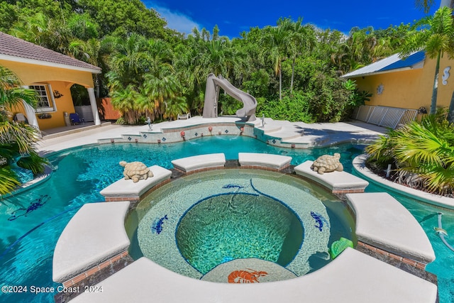 view of pool with a water slide, an in ground hot tub, and a patio area