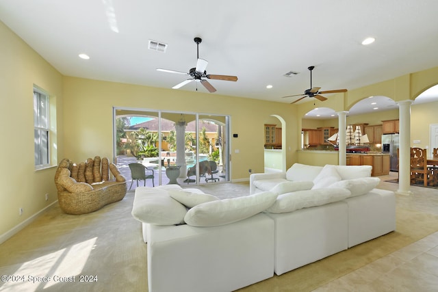 carpeted living room featuring decorative columns and ceiling fan