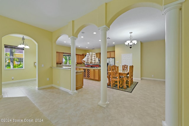 kitchen with pendant lighting, a notable chandelier, stainless steel fridge, and decorative columns