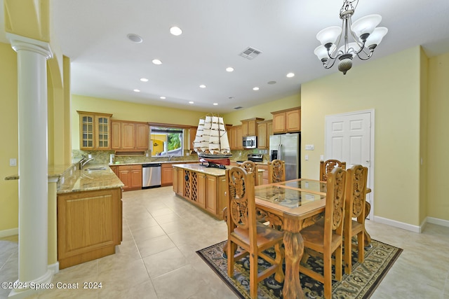 dining area with an inviting chandelier, sink, light tile patterned floors, and ornate columns