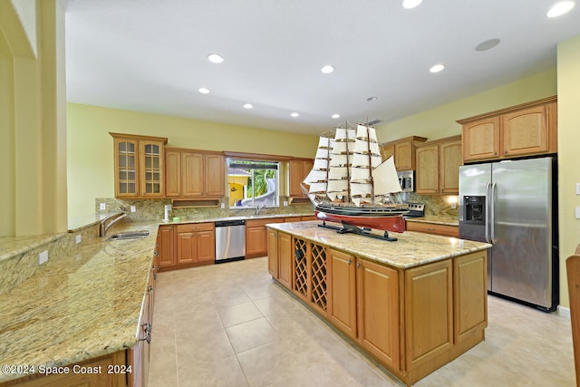 kitchen featuring light stone counters, light tile patterned floors, kitchen peninsula, a kitchen island, and stainless steel appliances