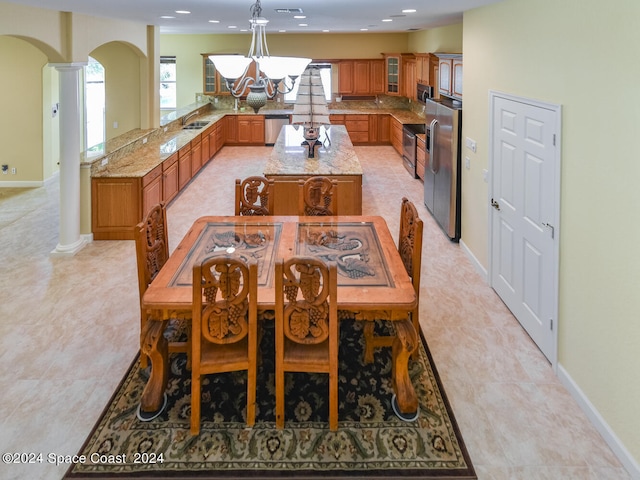 dining room with light tile patterned floors, a notable chandelier, sink, and decorative columns