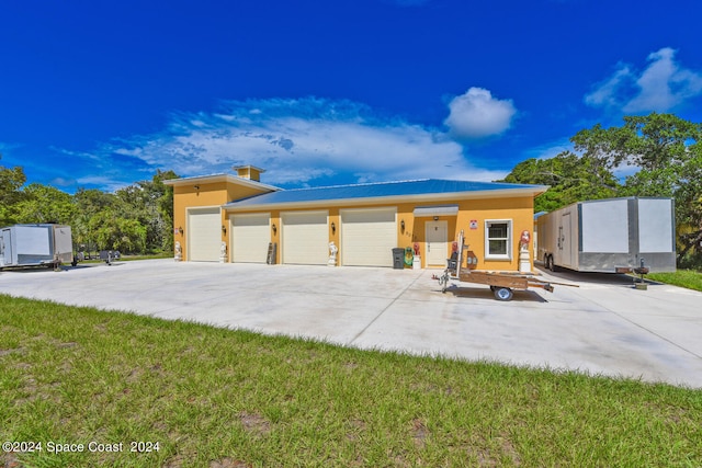 view of front of house with a storage unit, a garage, and a front lawn