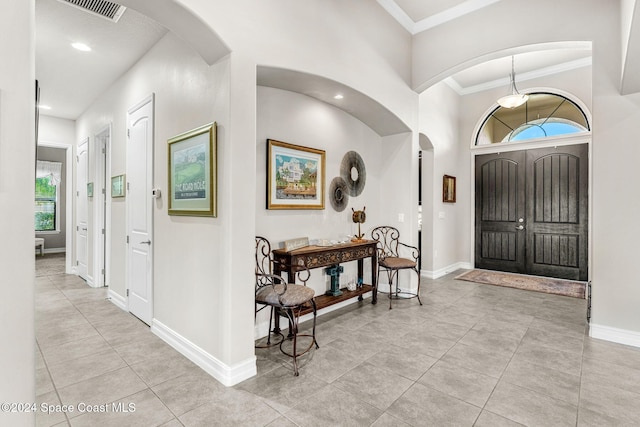 foyer entrance featuring ornamental molding and light tile patterned floors