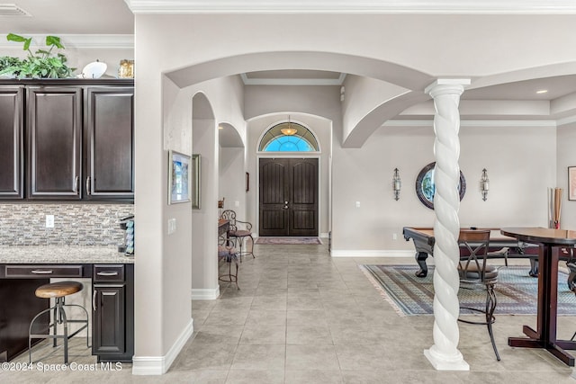 tiled foyer with ornamental molding and ornate columns