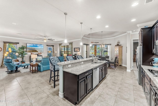 kitchen featuring an island with sink, stainless steel appliances, sink, a kitchen bar, and decorative light fixtures