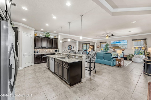 kitchen featuring sink, pendant lighting, ornamental molding, a breakfast bar area, and a kitchen island with sink