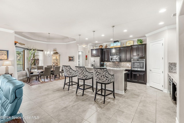 kitchen featuring dark brown cabinets, hanging light fixtures, a center island with sink, crown molding, and stainless steel appliances