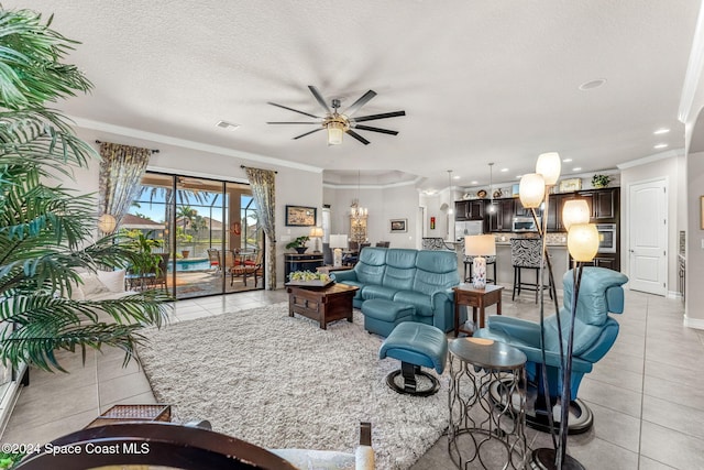 living room featuring ornamental molding, light tile patterned flooring, ceiling fan with notable chandelier, and a textured ceiling