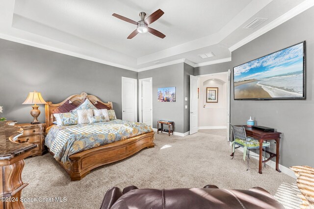 carpeted bedroom featuring ceiling fan, crown molding, and a tray ceiling