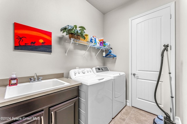 laundry room featuring sink, light tile patterned floors, washer and dryer, a textured ceiling, and cabinets