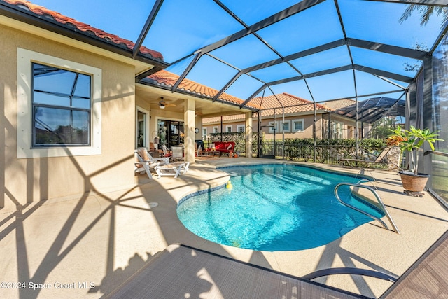 view of swimming pool with a patio, glass enclosure, and ceiling fan