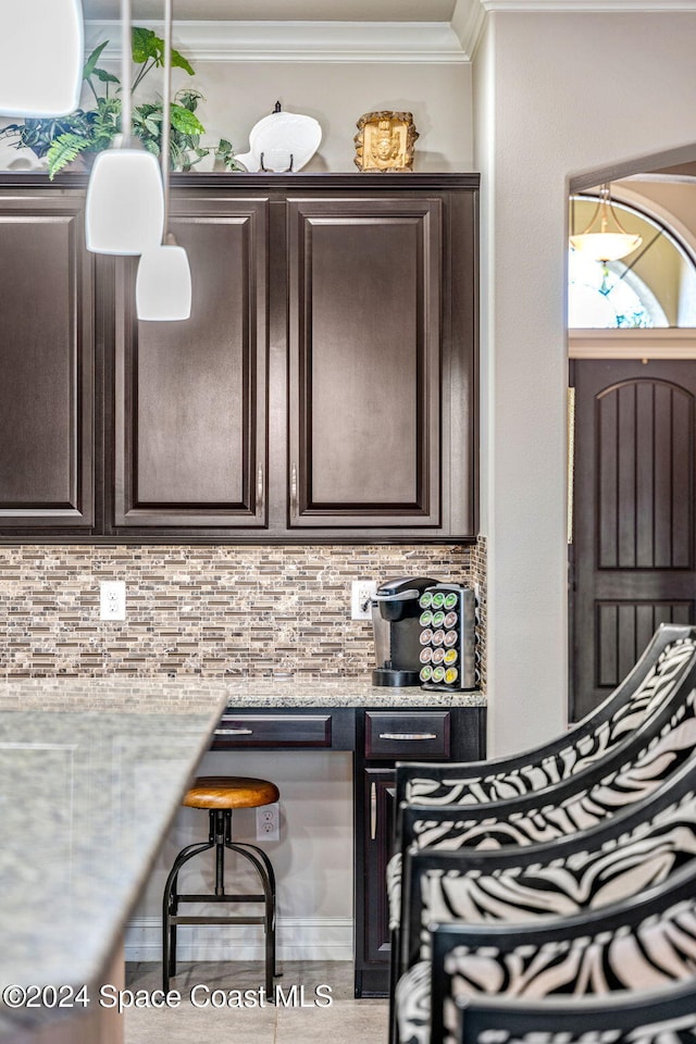 kitchen with light stone counters, crown molding, decorative backsplash, and dark brown cabinetry