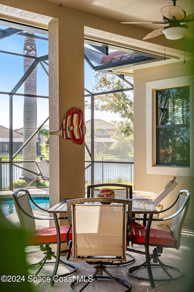 dining room with a water view, ceiling fan, a textured ceiling, and plenty of natural light