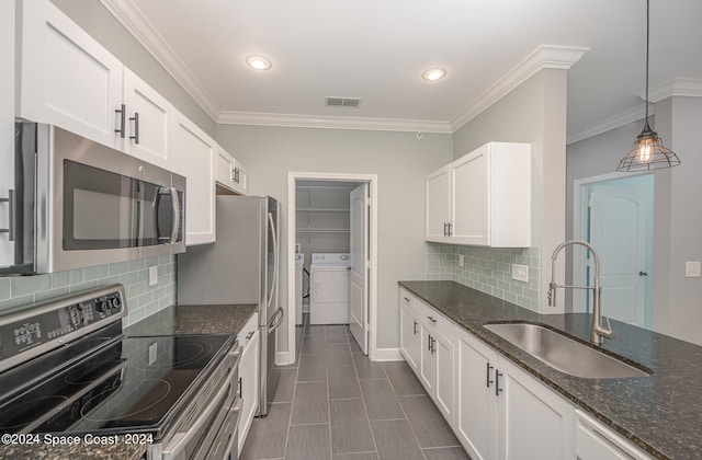 kitchen with sink, white cabinets, appliances with stainless steel finishes, dark stone countertops, and washer and clothes dryer