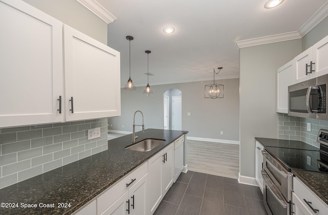 kitchen with white cabinets, pendant lighting, stainless steel appliances, dark stone counters, and sink