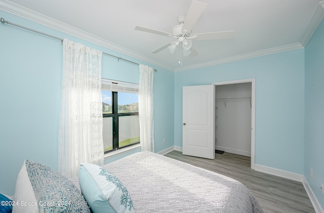 bedroom with a closet, light wood-type flooring, ceiling fan, and crown molding