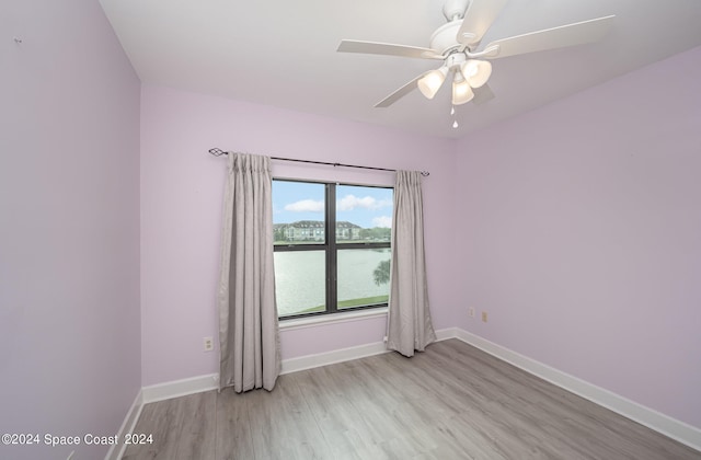 spare room with light hardwood / wood-style floors, a water view, and ceiling fan