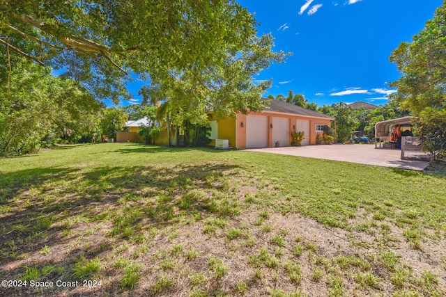 8053 S Indian River Dr, Ft Pierce, FL 34982 - view of green lawn featuring a garage and concrete driveway