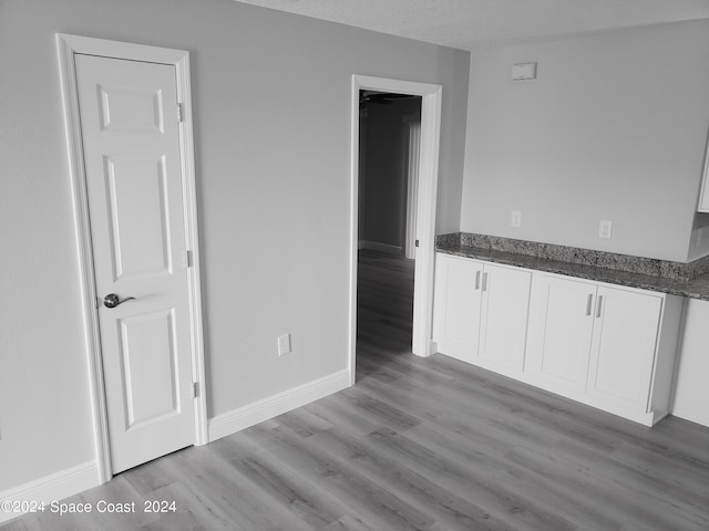 interior space with white cabinets, light hardwood / wood-style floors, and a textured ceiling