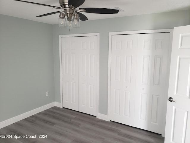 unfurnished bedroom with hardwood / wood-style floors, two closets, and ceiling fan