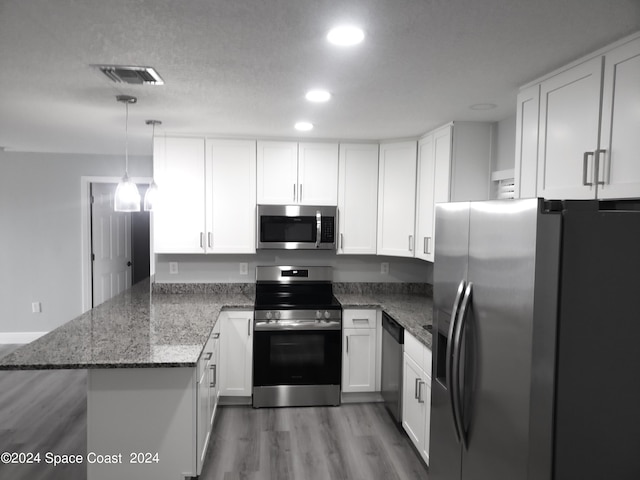 kitchen featuring white cabinets, appliances with stainless steel finishes, kitchen peninsula, and decorative light fixtures