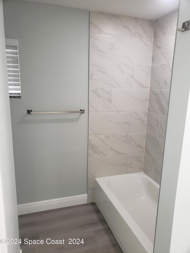 bathroom with wood-type flooring and tiled shower / bath