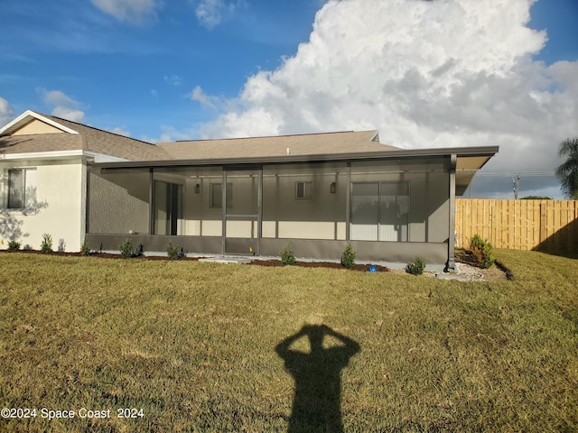 back of house with a sunroom and a lawn