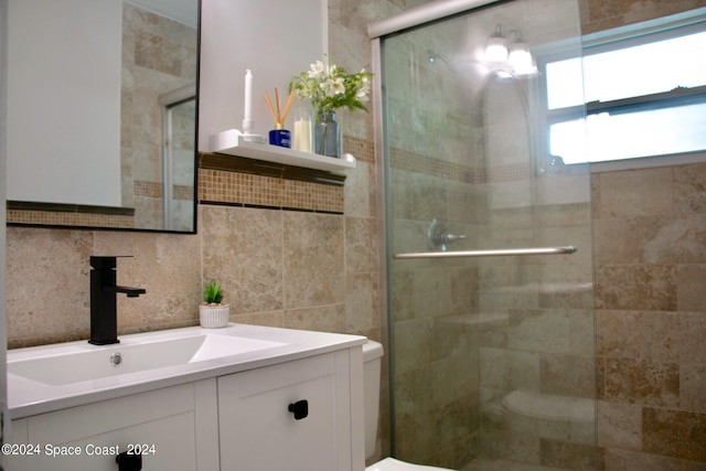 bathroom featuring backsplash, vanity, toilet, and a shower with shower door