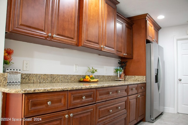 kitchen with stainless steel refrigerator with ice dispenser and light stone countertops