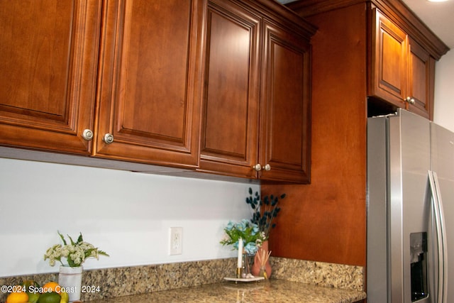 kitchen featuring light stone counters and stainless steel fridge