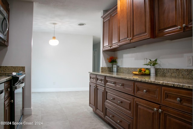 kitchen with decorative light fixtures, appliances with stainless steel finishes, and dark stone counters