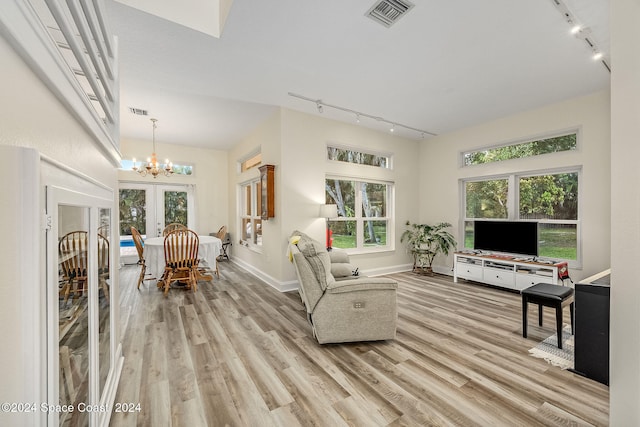 living room featuring rail lighting, french doors, and light hardwood / wood-style floors