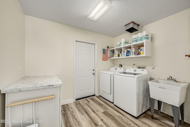 laundry area featuring a textured ceiling, light wood-type flooring, sink, and washer and dryer