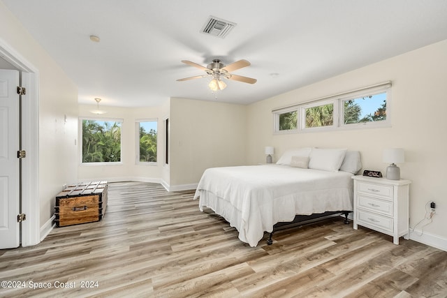 bedroom with ceiling fan, light wood-type flooring, and multiple windows