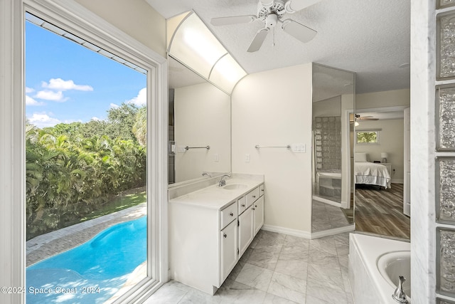 bathroom featuring ceiling fan, a washtub, vanity, and a textured ceiling