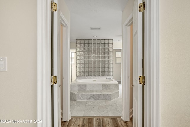 bathroom with hardwood / wood-style flooring and a relaxing tiled tub