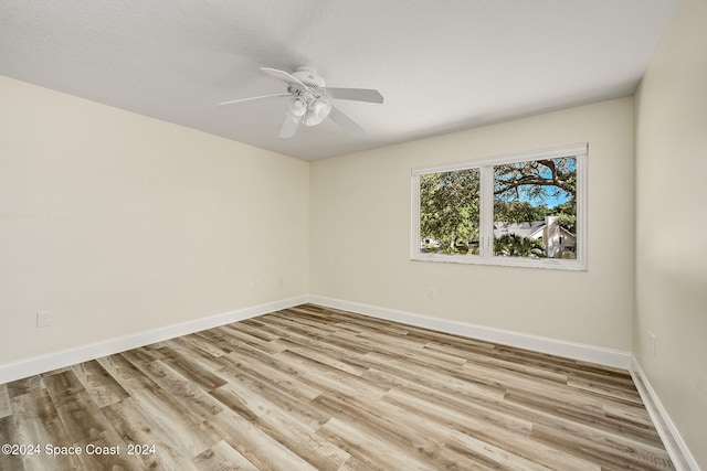 empty room with a textured ceiling, light wood-type flooring, and ceiling fan