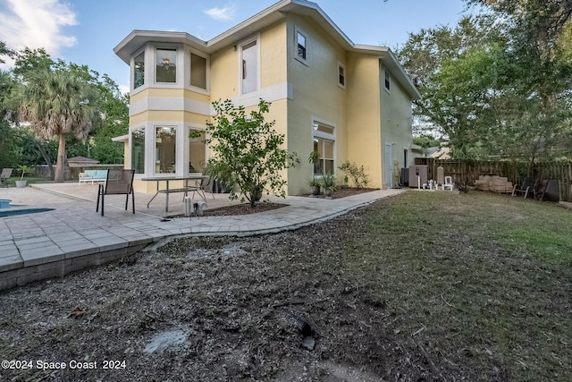 rear view of house featuring central air condition unit, a lawn, and a patio area