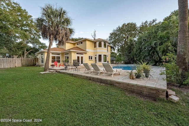 rear view of house with a fenced in pool, a yard, and a patio