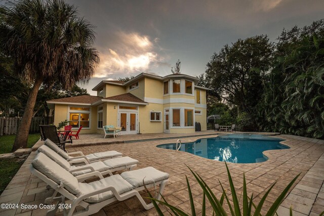 1165 Old Parsonage Dr, Merritt Island, FL 32952 - back of property at dusk featuring french doors, stucco siding, a patio, and fence