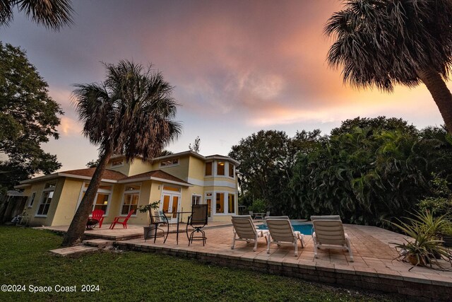 1165 Old Parsonage Dr, Merritt Island, FL 32952 - back of house at dusk with a patio area, french doors, stucco siding, an outdoor pool, and a yard