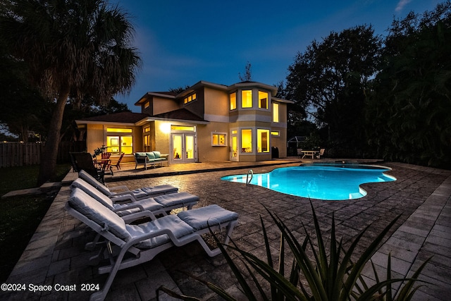 pool at twilight with french doors and a patio