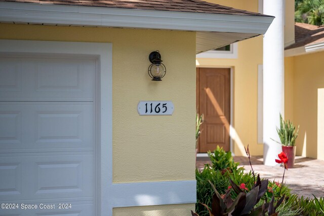 1165 Old Parsonage Dr, Merritt Island, FL 32952 - doorway to property featuring stucco siding, a garage, and roof with shingles