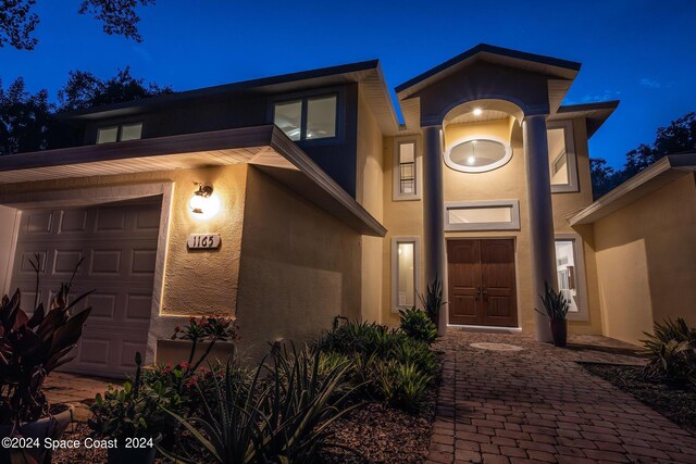 1165 Old Parsonage Dr, Merritt Island, FL 32952 - exterior entry at twilight featuring stucco siding and an attached garage