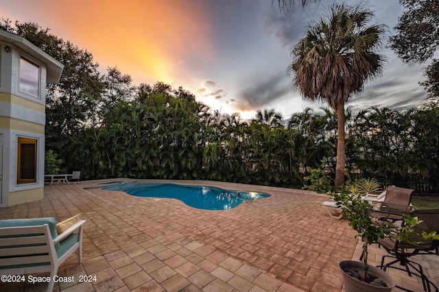 pool at dusk featuring a patio area